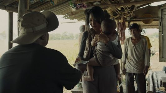 Gambar 4. Seorang perempuan menerima sejumlah uang sambil menggendong anaknya.